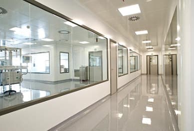 A cleanroom corridor with modular wall panels, flush glazing and seamless flooring.