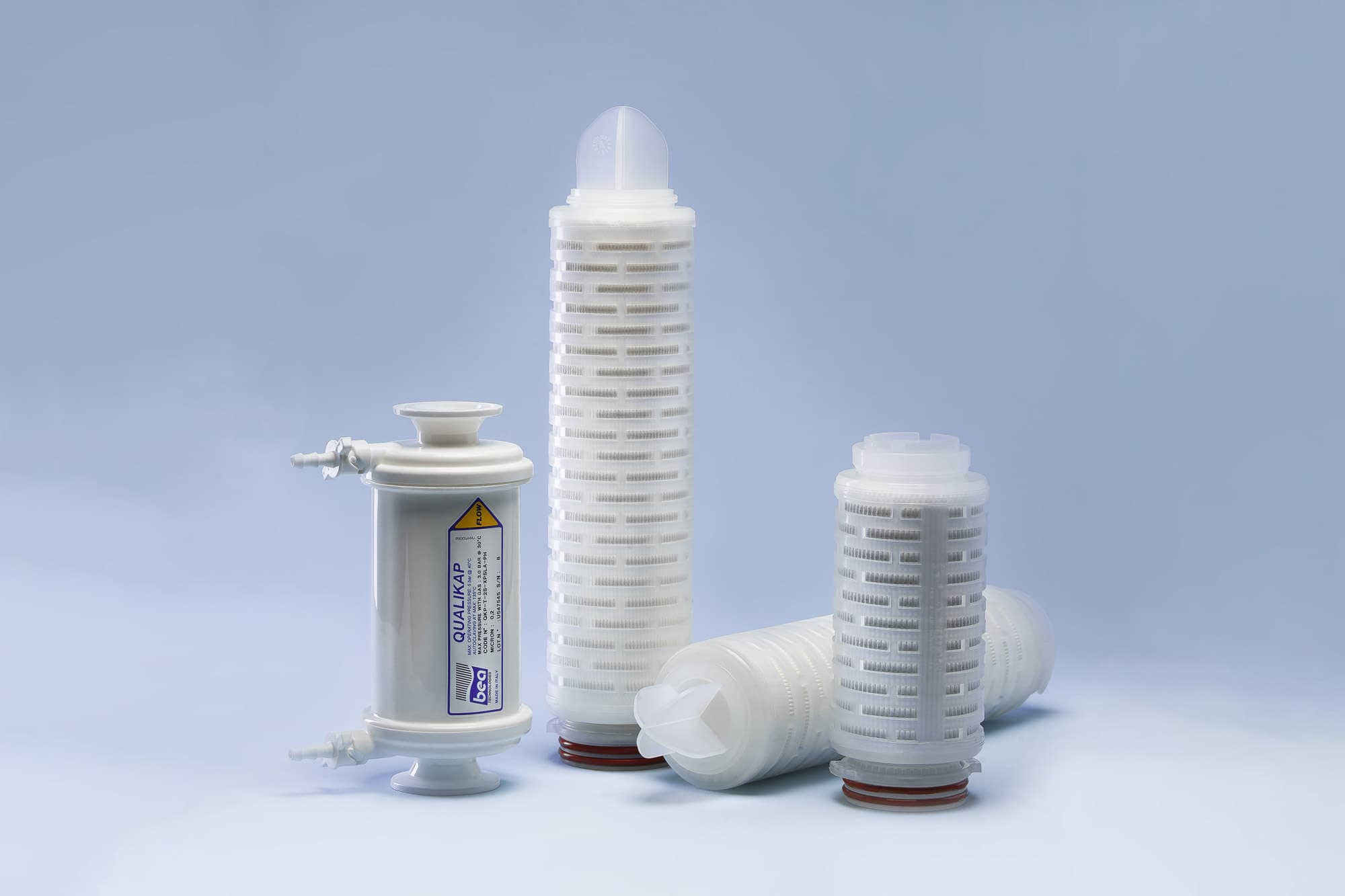 Pleated filter cartridges and a capsule filter arranged on a light surface.
